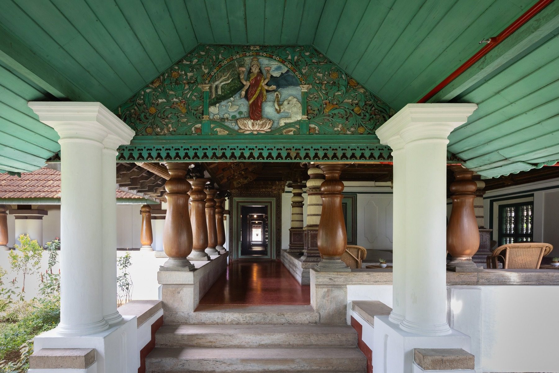 Der traditionell verzierte Eingangsportikus des Kalari Kovilakom empfängt Gäste mit klassischer Kerala-Architektur und hinduistischer Wandmalerei.